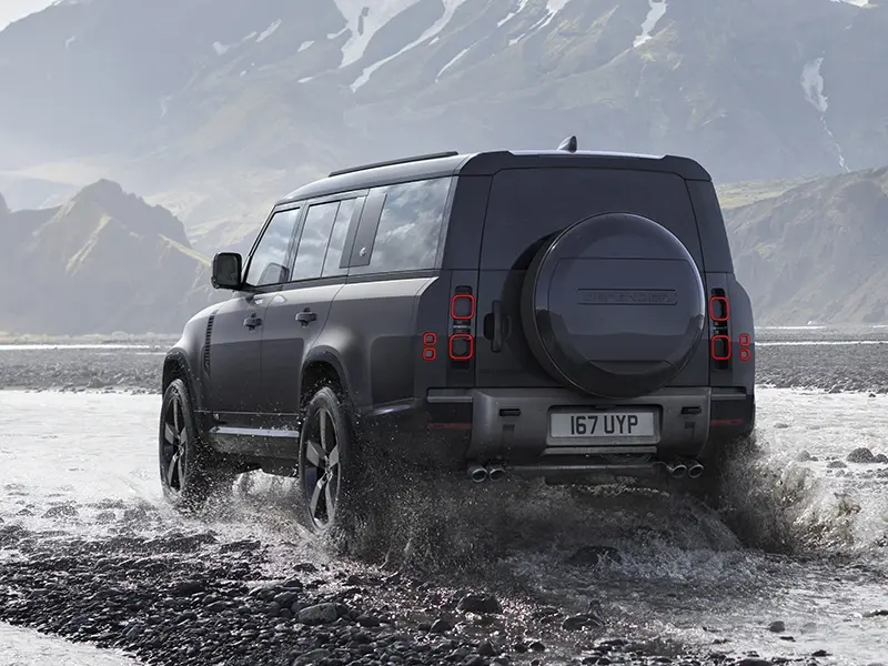 Carpathian Grey Land Rover Defender 130 V8 crossing a stream in rugged mountainous terrain