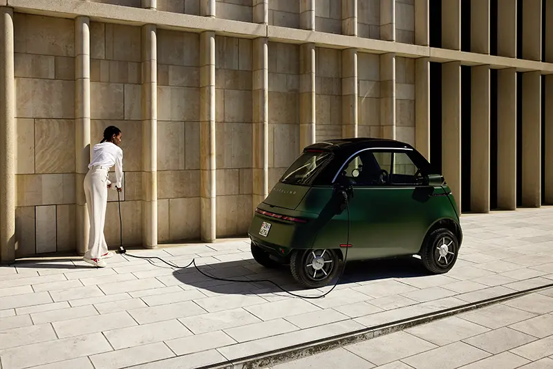 Microlino EV Bubble car plugged into a wall charger