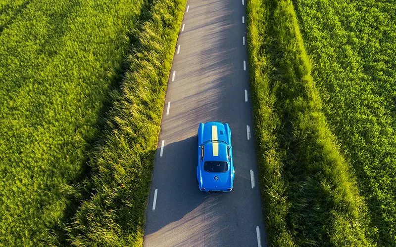 Volvo P1800 Cyan on a long country road