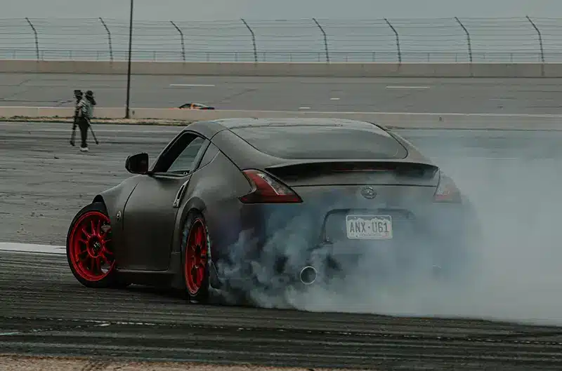 Matte black Nissan 370Z ready to take off on a racetrack, exuding power and speed.