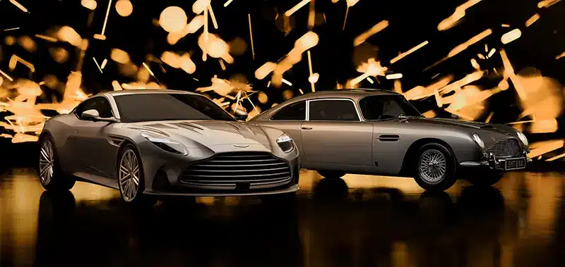 Aston Martin DB12 Goldfinger Edition next to an original DB5 with Goldfinger backdrop.