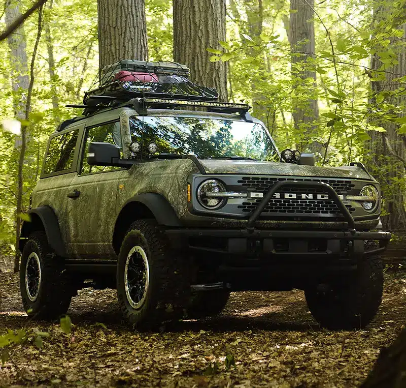 Ford Bronco Sasquatch Searcher SUV navigating forest trails.