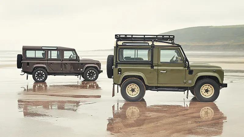 Custom Retro Classic Defender V8 90 and 110 body models parked on a wet beach, demonstrating off-road capabilities with rugged styling and powerful V8 performance.