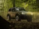 Bronco Sasquatch Searcher SUV camouflaged in dense forest off-road terrain.