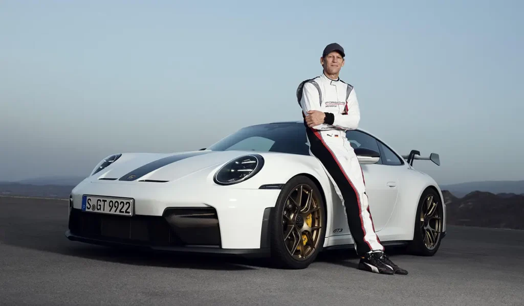 Jörg Bergmeister, Porsche Brand Ambassador, standing next to a white 2024 Porsche 911 GT3 Weissach Package.
