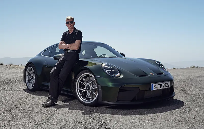 Walter Röhrl, Porsche Brand Ambassador, next to a green 2024 Porsche 911 GT3 Touring Package.