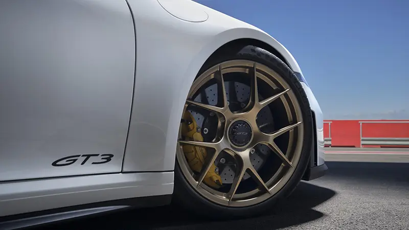 Close-up view of the 2024 Porsche 911 GT3’s front wheel and red brake caliper.