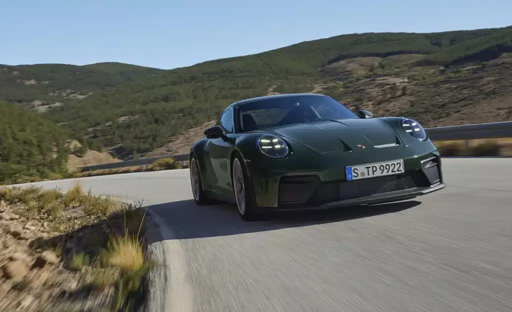 Green 2024 Porsche 911 GT Touring Package driving on a winding road