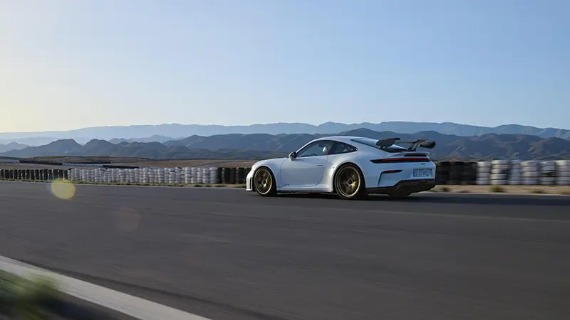 Side view of the 2024 Porsche 911 GT speeding on a race track during a test day.