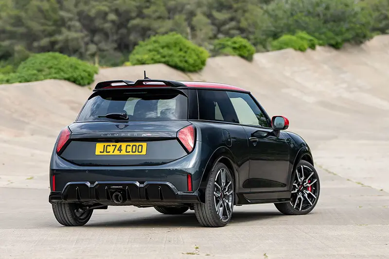 Rear 3/4 view of the new Mini John Cooper Works Hatchback displaying it's centered exhaust and a sporty spoiler.