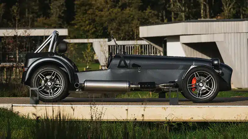 Side profile of the Caterham Seven CSR Twenty with a side-mounted exhaust in the countryside.