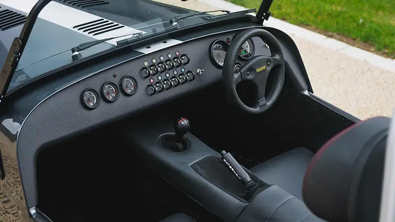 Interior of the Caterham Seven CSR Twenty with premium features like a satin carbon dashboard and leather Momo steering wheel.