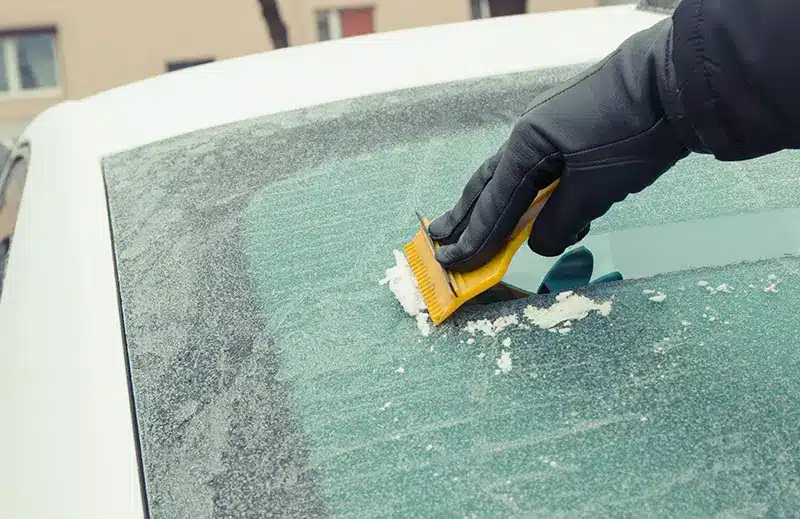 ice being scraped off a car windscreen in cold weather