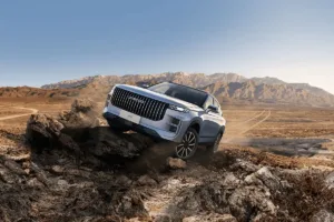 New Jaecoo 7 SUV climbing rocky mountain in desert terrain.