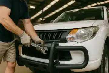 Mechanic removing a bull bar from a 4WD ute during vehicle modification