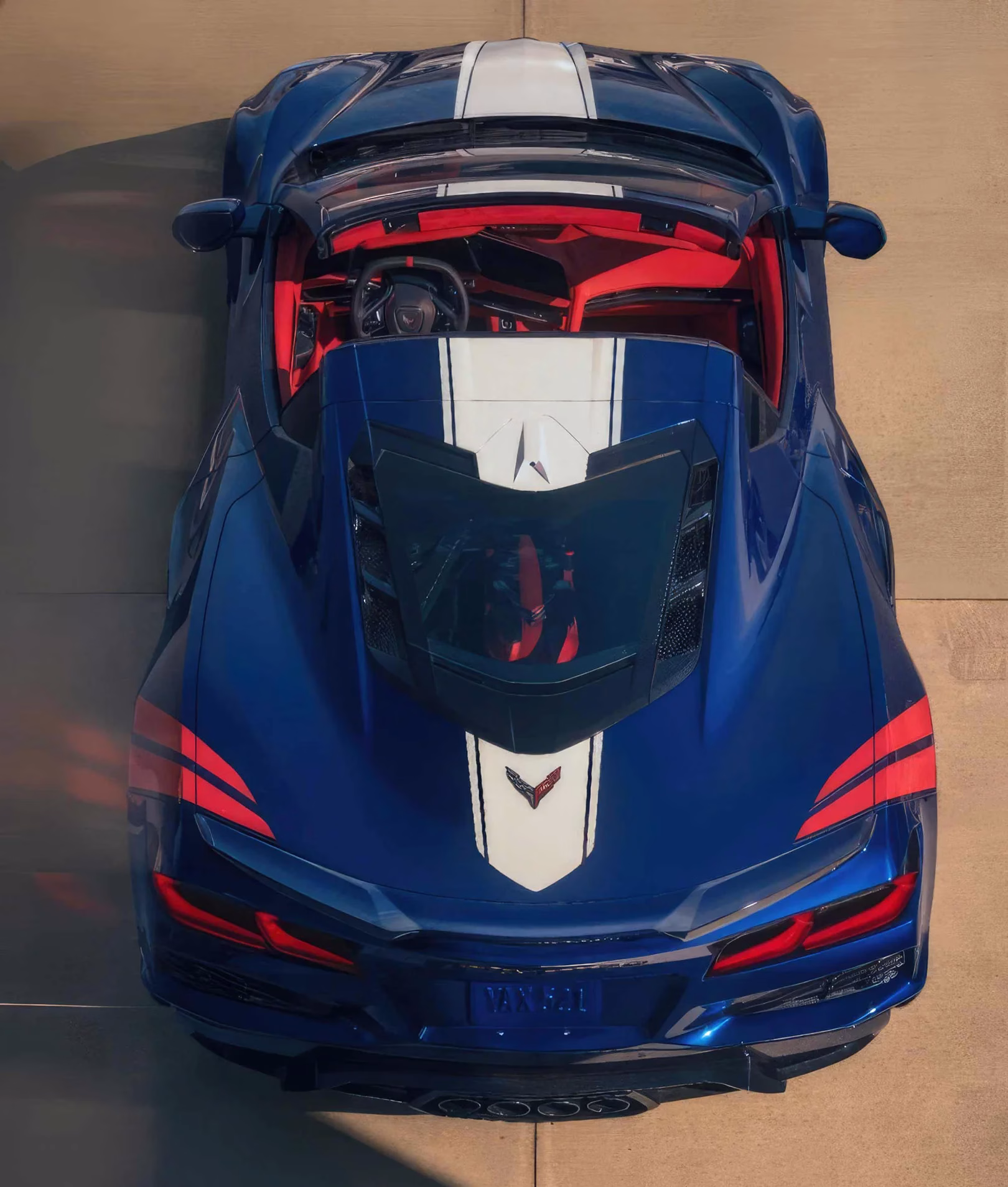 Overhead rear view of a blue 2027 Chevrolet Corvette Grand Sport convertible with white and red heritage graphics
