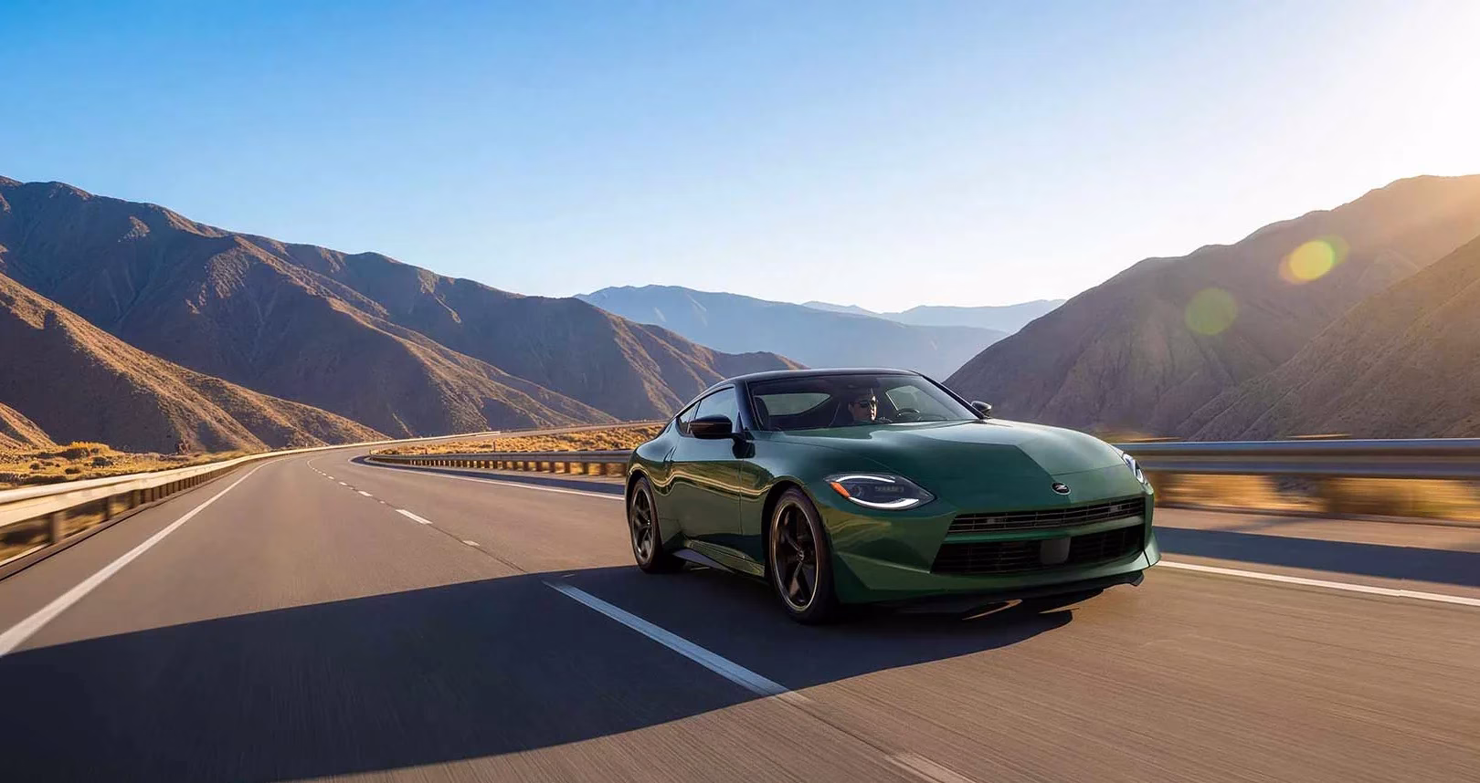 Green 2027 Nissan Z driving on a mountain road in bright sunlight