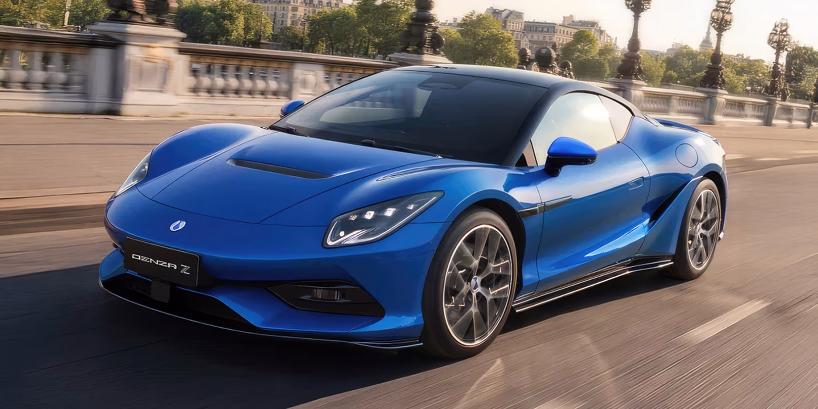 Blue BYD Denza Z coupe driving across a Paris bridge, front three-quarter, motion blur