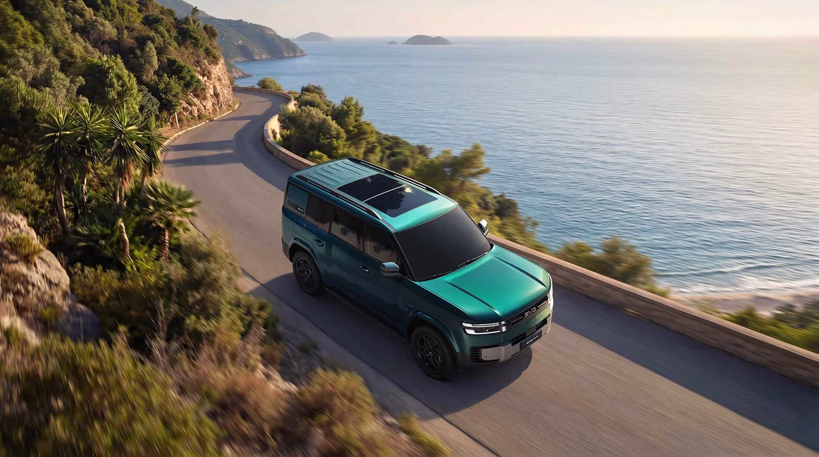 Green BYD Ti7 seen from above while driving along a coastal road