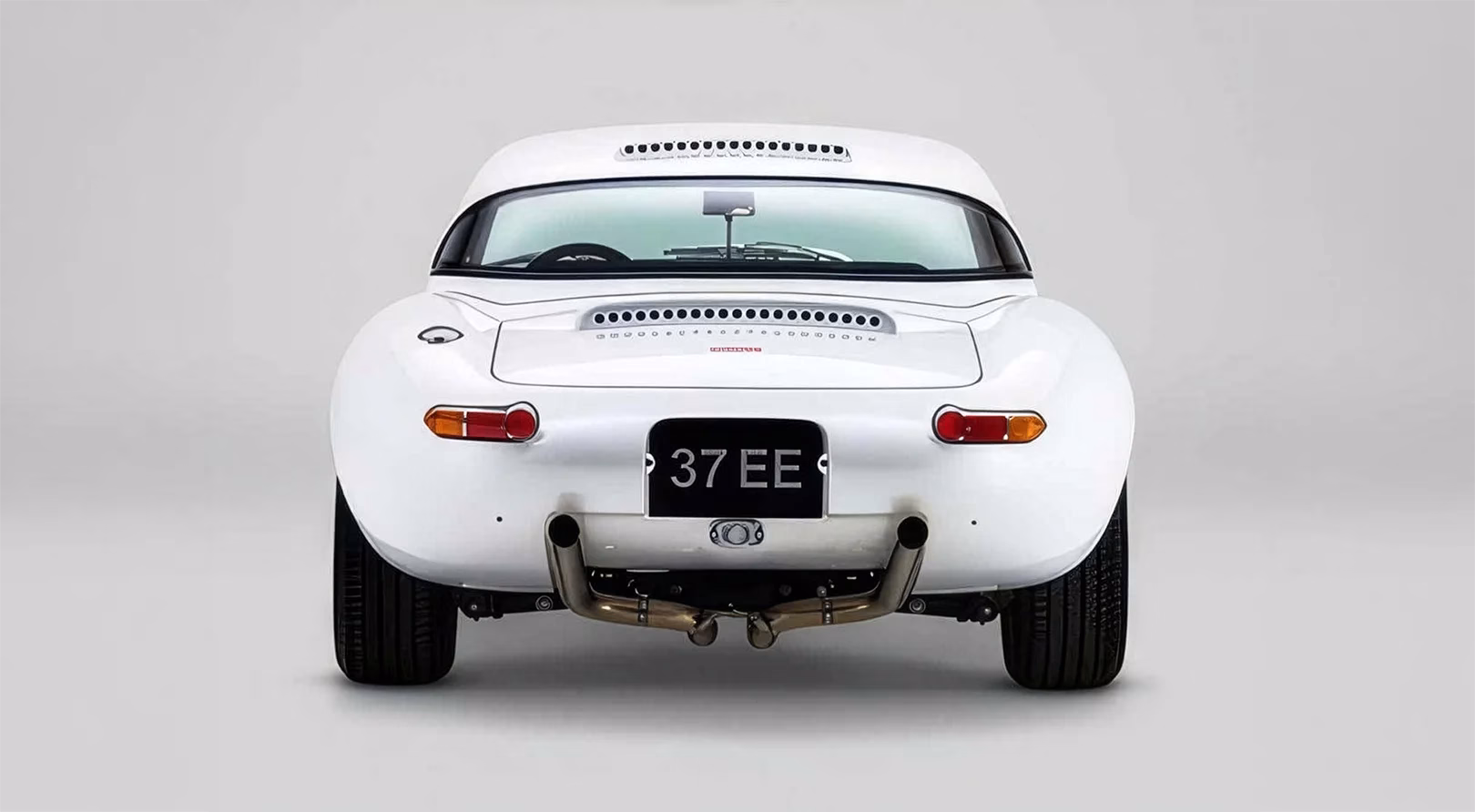Rear view of the white Eagle Lightweight GTR Jaguar E-Type showing the twin exhaust and 37 EE plate