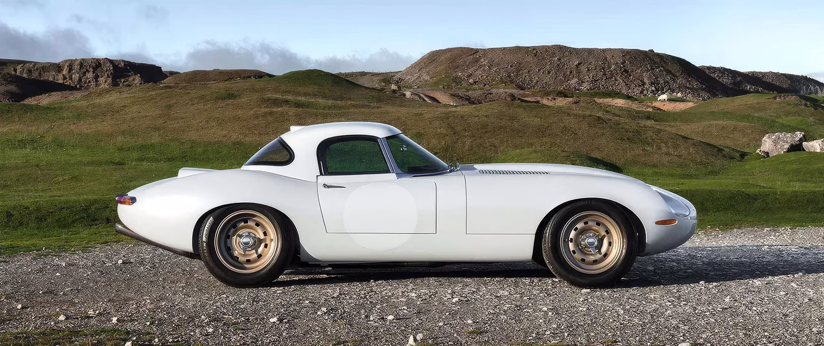 White Eagle Lightweight GTR Jaguar E-Type side profile parked on gravel with hills behind