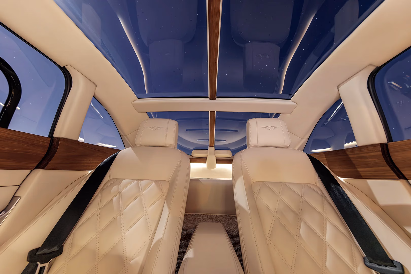 View up at the tinted glass roof of the Morgan Midsummer Coupé from between the cream leather seats, wood spine down the centre