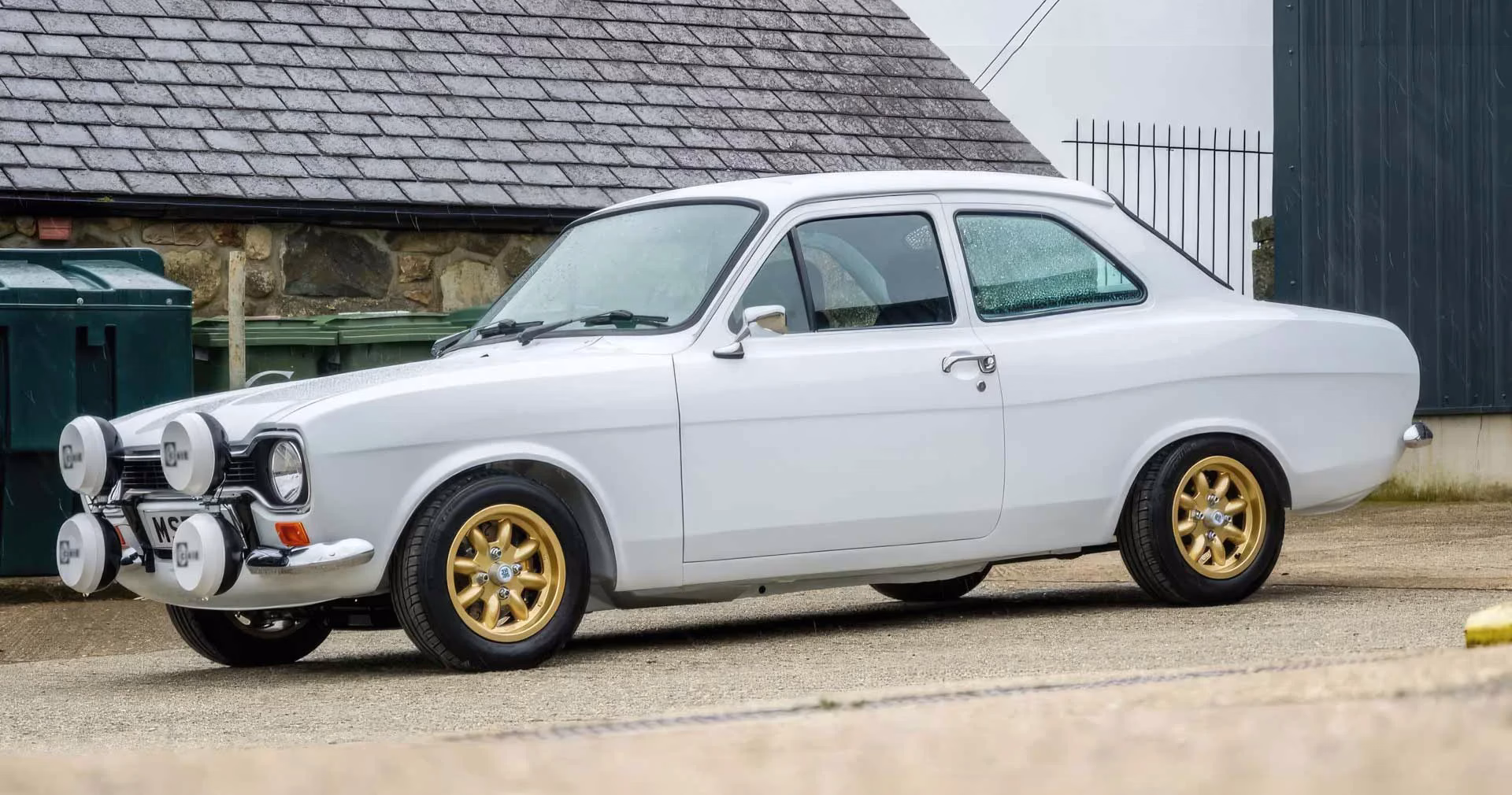White MST Mk1 Sports in a wet Welsh yard with gold wheels and spotlamps