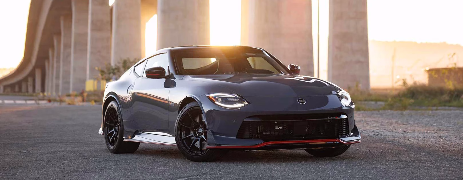 Grey Nissan Z NISMO parked beneath an elevated road at sunset