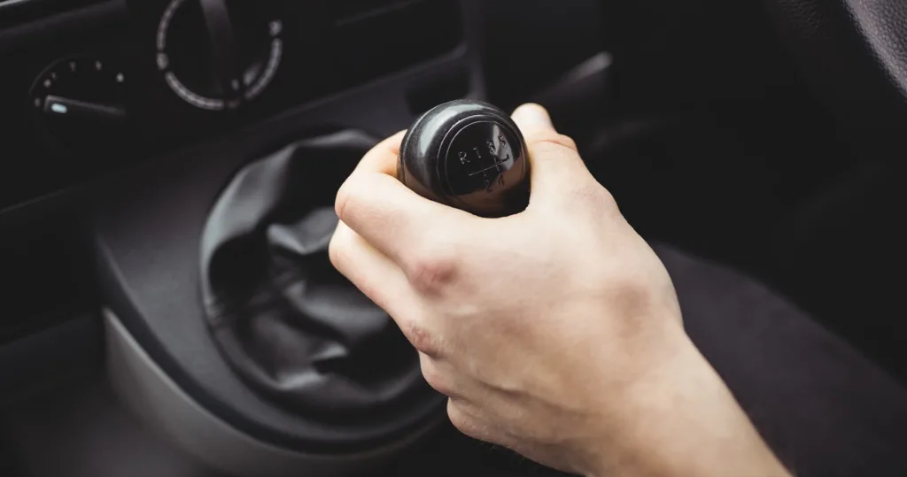 Driver's hand resting on a manual transmission gear shift knob