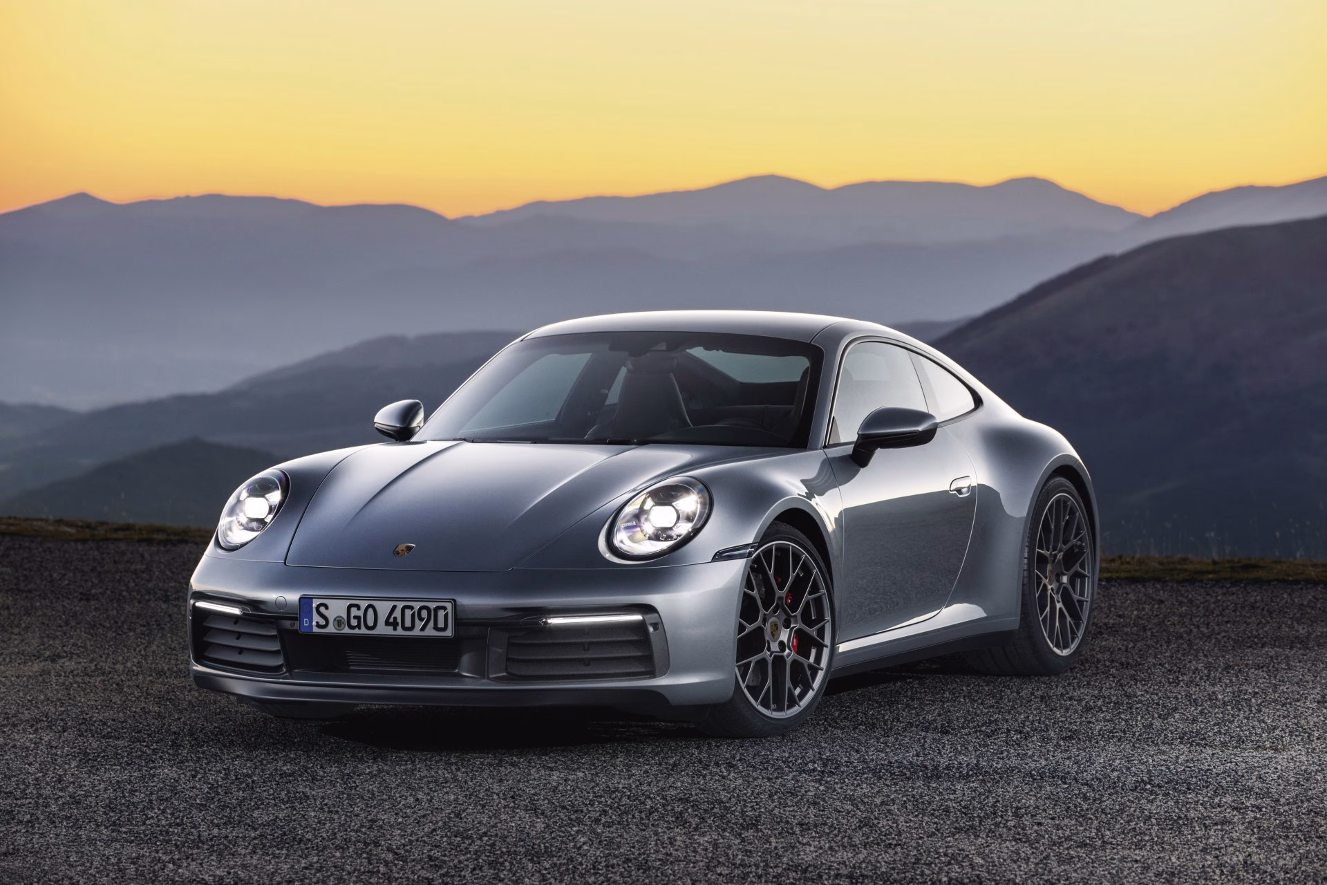 Grey Porsche 911 992 Carrera parked on a mountain road at sunset