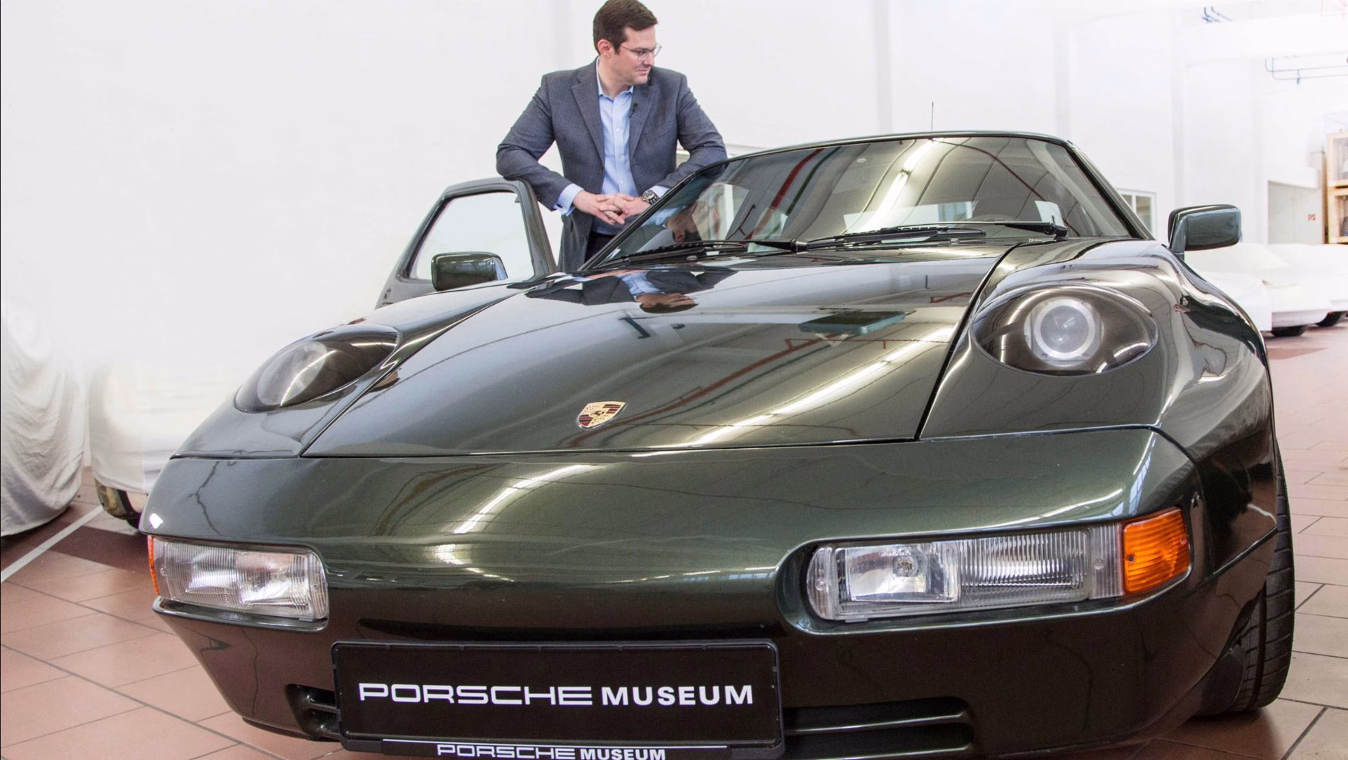 Dark green Porsche 928 in the Porsche Museum store with a man beside it